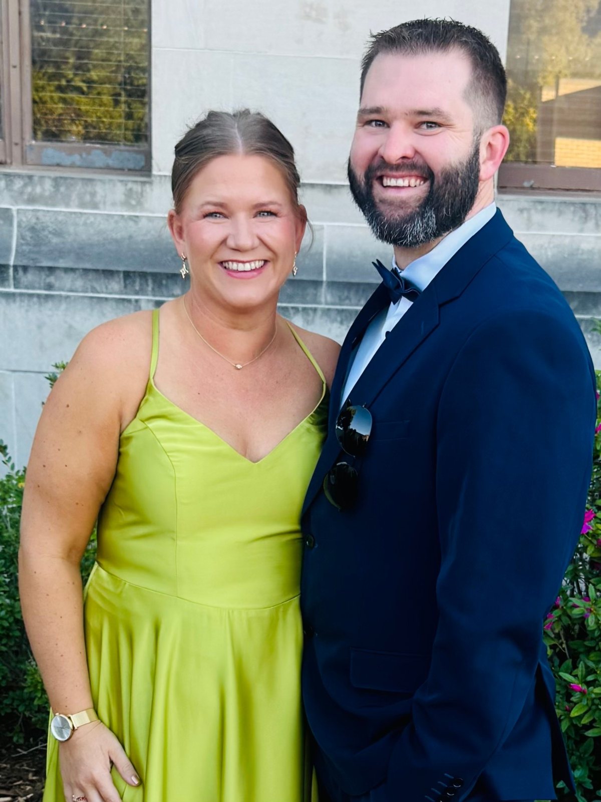 Tara in a green gown and Tyler in a navy suit, smiling together