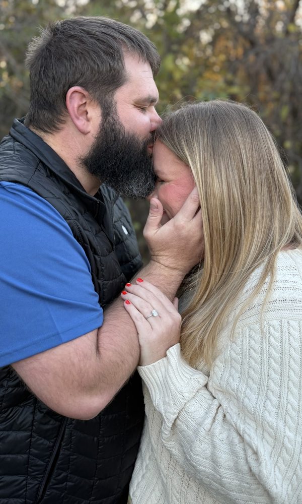 Tyler kissing Tara on the forehead, her engagement ring showing